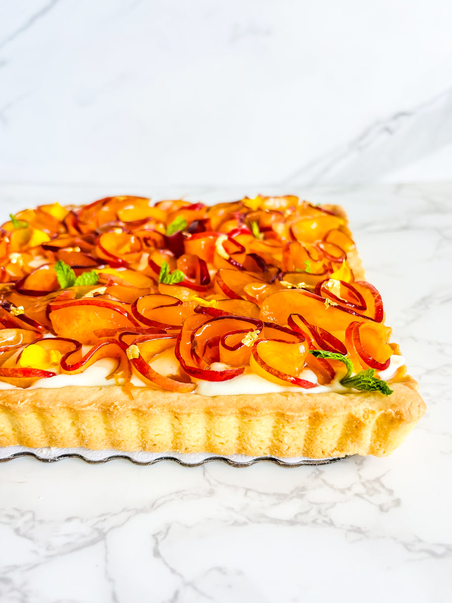 This is a peach shortbread tart. It is made with a lemon buttery shortbread shell and Italian pastry cream filling and decorated with fresh peach ruffles and mini mint leaves. 