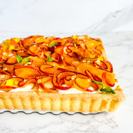 This is a peach shortbread tart. It is made with a lemon buttery shortbread shell and Italian pastry cream filling and decorated with fresh peach ruffles and mini mint leaves. 