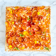 This is a peach shortbread tart. It is made with a lemon buttery shortbread shell and Italian pastry cream filling and decorated with fresh peach ruffles and mini mint leaves. 