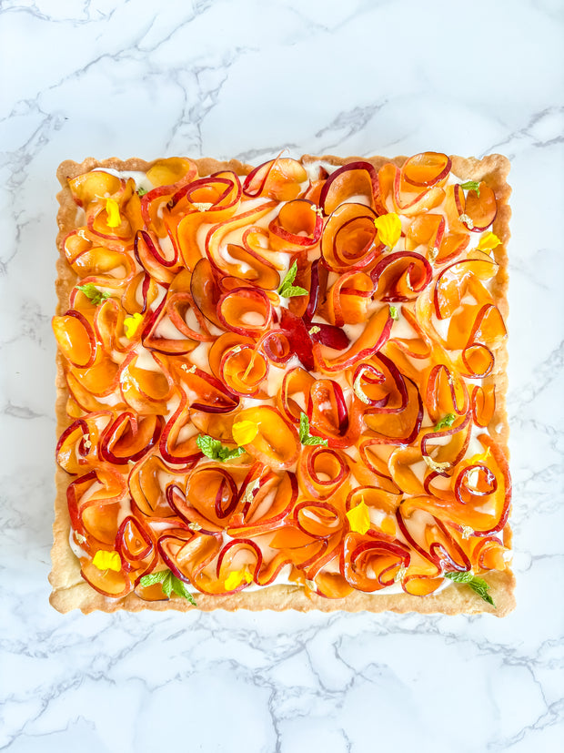 This is a peach shortbread tart. It is made with a lemon buttery shortbread shell and Italian pastry cream filling and decorated with fresh peach ruffles and mini mint leaves. 