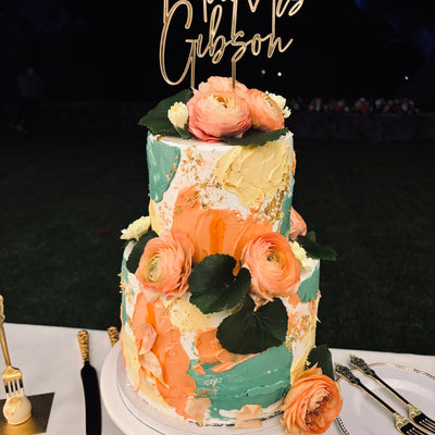 Wedding cakes Honolulu. Round wedding cake with vanilla buttercream. Decorated with fresh ranunculus and bride and groom names topper. 
