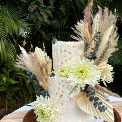 Boho wedding cakes Honolulu. Round two-tier boho wedding cake with pampass grass decors, dry eucalyptus, fresh flowers. The cake is decorated with stencils and gold leaf.