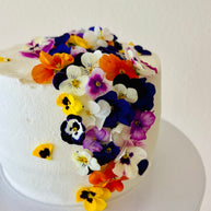 Custom cakes Oahu by an Italian Pastry Chef. This cake is made with vanilla sponge, italian pastry cream filling, elderflower chantilly frosting and decorated with edible pansies  and violas flowers.