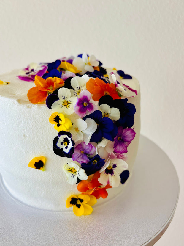 Custom cakes Oahu by an Italian Pastry Chef. This cake is made with vanilla sponge, italian pastry cream filling, elderflower chantilly frosting and decorated with edible pansies  and violas flowers.