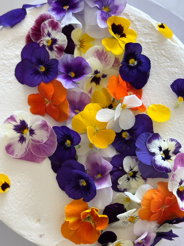 Custom cakes Oahu by an Italian Pastry Chef. This cake is made with vanilla sponge, italian pastry cream filling, elderflower chantilly frosting and decorated with edible pansies  and violas flowers.