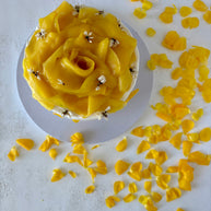 This is a round vanilla and mango cake. It is made of vanilla sponge, white chocolate chantilly, and fresh mango bites. It is decorated with a flower made of mango slices and fresh edible flowers.
