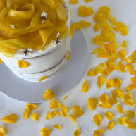 This is a round vanilla and mango cake. It is made of vanilla sponge, white chocolate chantilly, and fresh mango bites. It is decorated with a flower made of mango slices and fresh edible flowers.