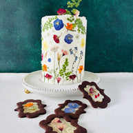 One tier white round cake. The cake is decorated with beautiful pressed flowers.