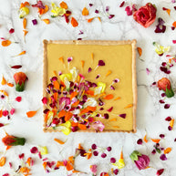 This is a square shortbread tart made with a lemony shortbread shell, a fresh Hawaiian mango filling, decorated with a garden of edible flower petals. 