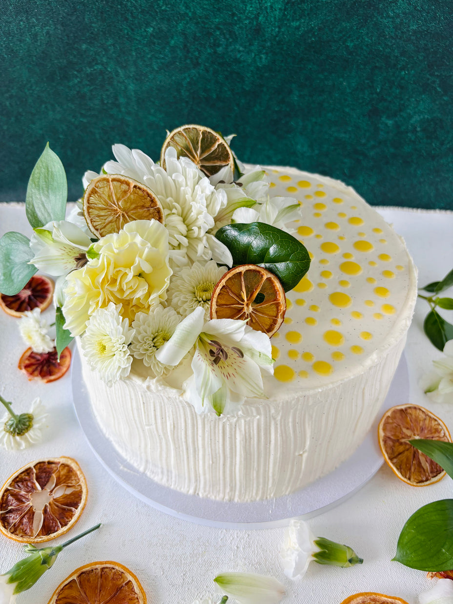 This is a 1 tier custom cake, made wirh vanilla sponge, lemon curd filling, white chocolate chantilly frosting. Decorated with dried citruses, fresh white flowers and leaves. 