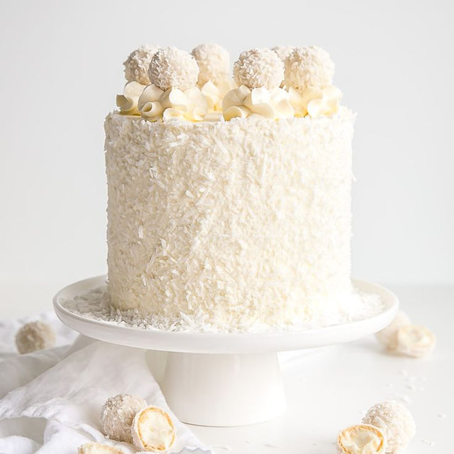 A one-tiered coconut chiffon cake made with moist vanilla sponge, coconut cream filling, and coconut flakes, it is decorated with coconut flakes and Raffaello chocolates.