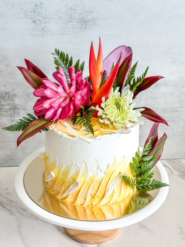 Custom Cakes for Every Occasion. Honolulu custom cakes. This round, one-tier cake is made with vanilla sponge, lemon filling, and Swiss buttercream frosting. It is decorated with fresh Hawaiian flowers.